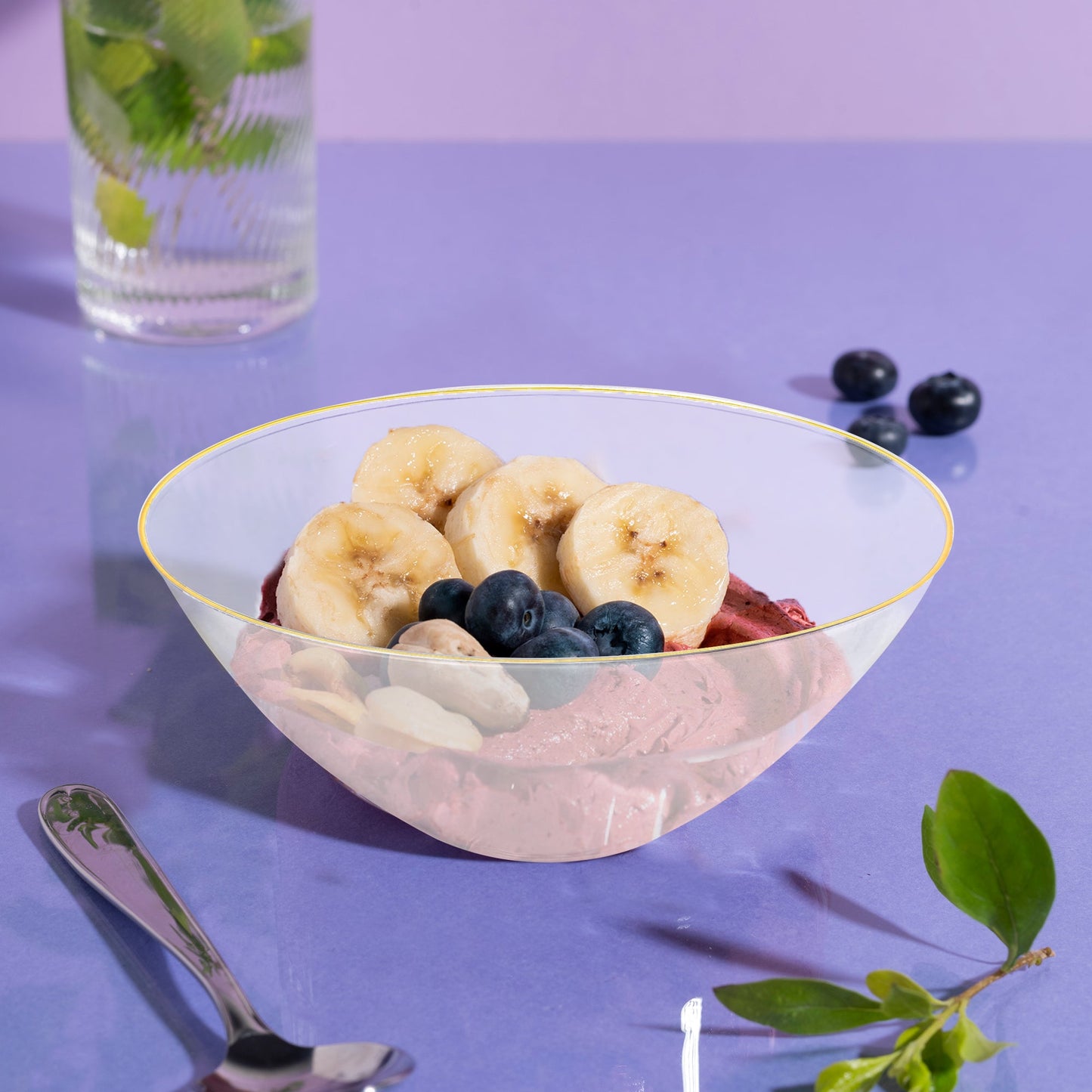 Clear with Gold Rim Organic Round Disposable Plastic Bowl (32 oz.) showcasing a delightful mix of banana slices, blueberries, and a scoop of ice cream