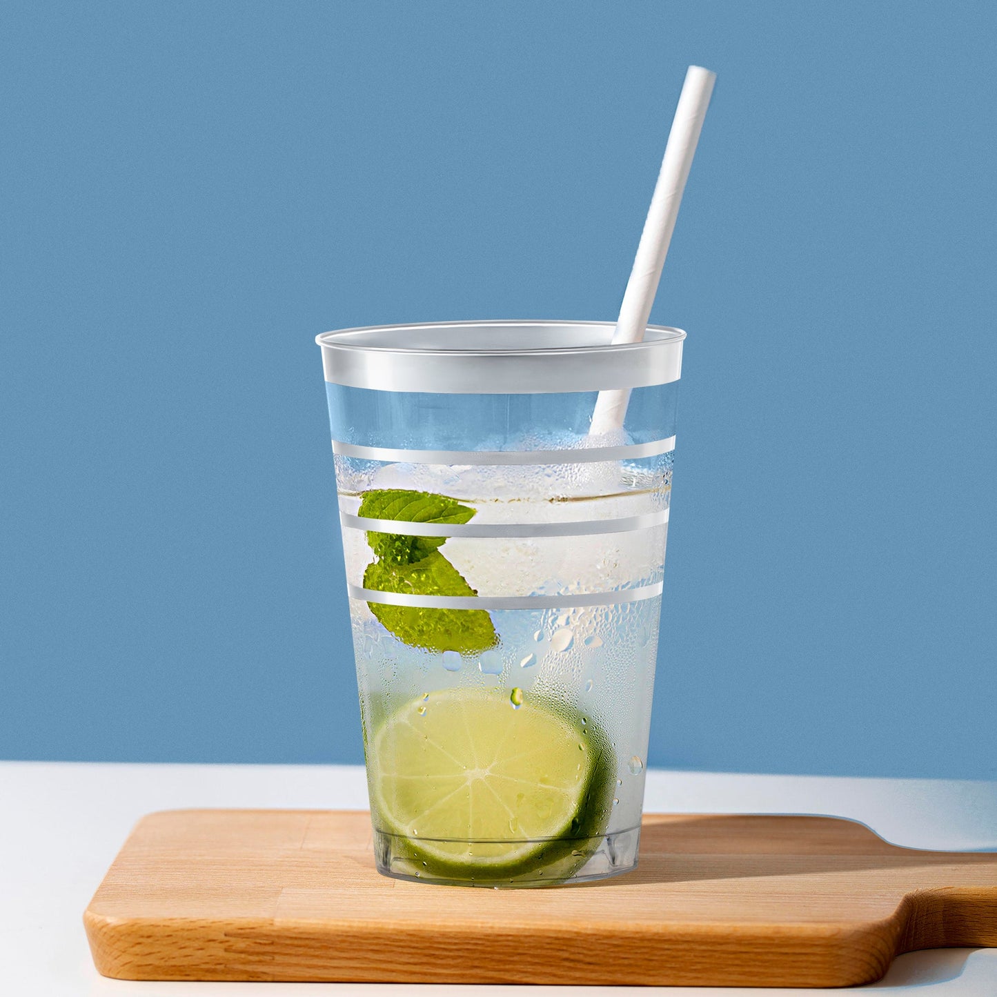 Elegant 12 oz. tumblers with silver stripes on a dinner table, perfect for stylish disposable drink service