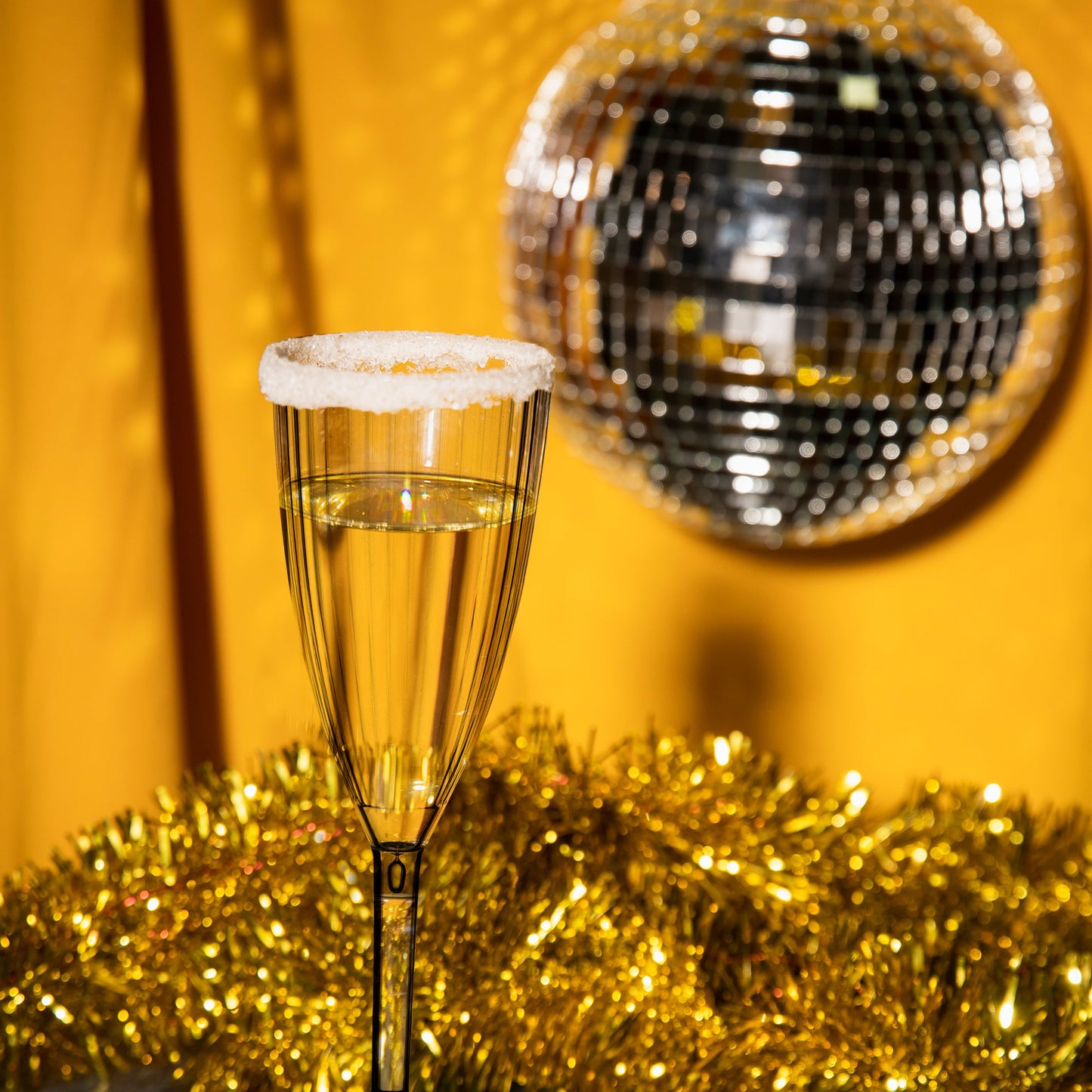 Elegant plastic champagne flutes with clear stripes featured on a white tablecloth with golden accents