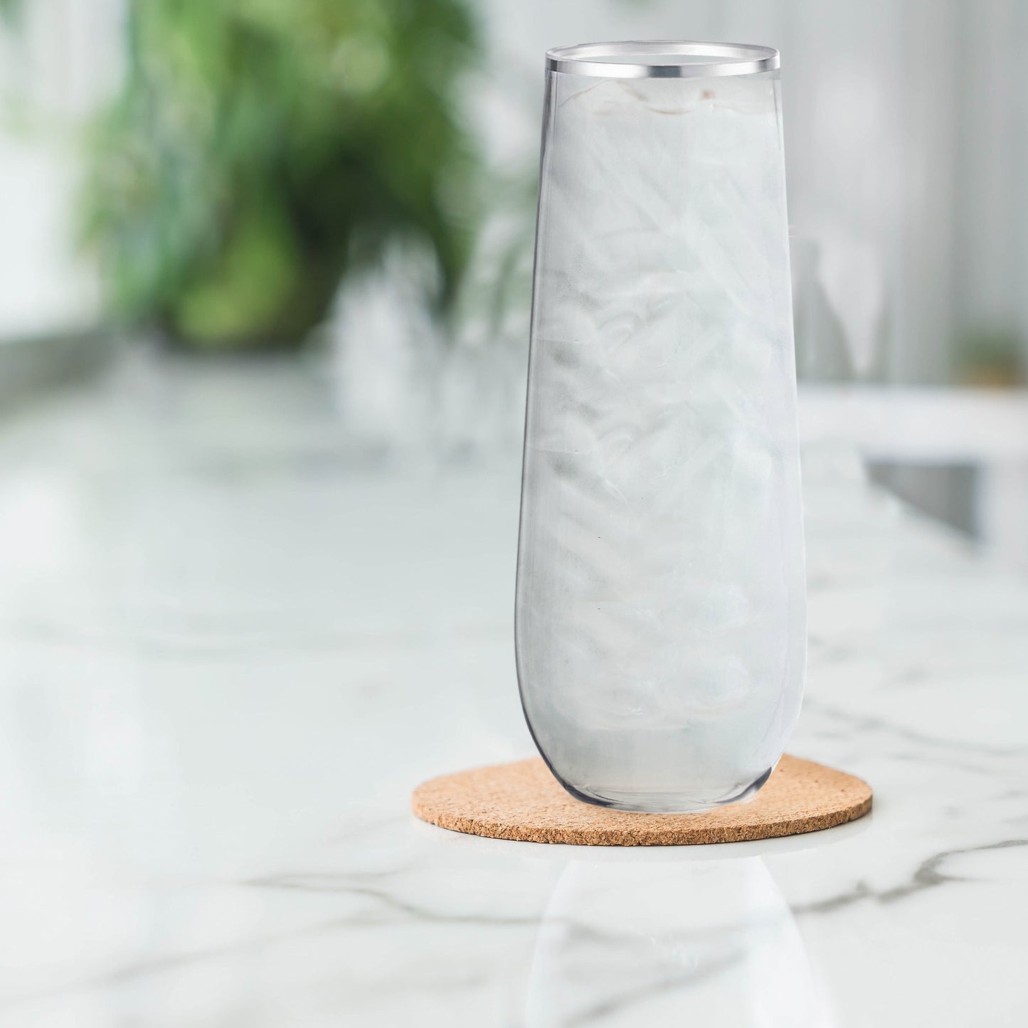 Stemless plastic champagne flutes with silver detail placed on a wedding reception table