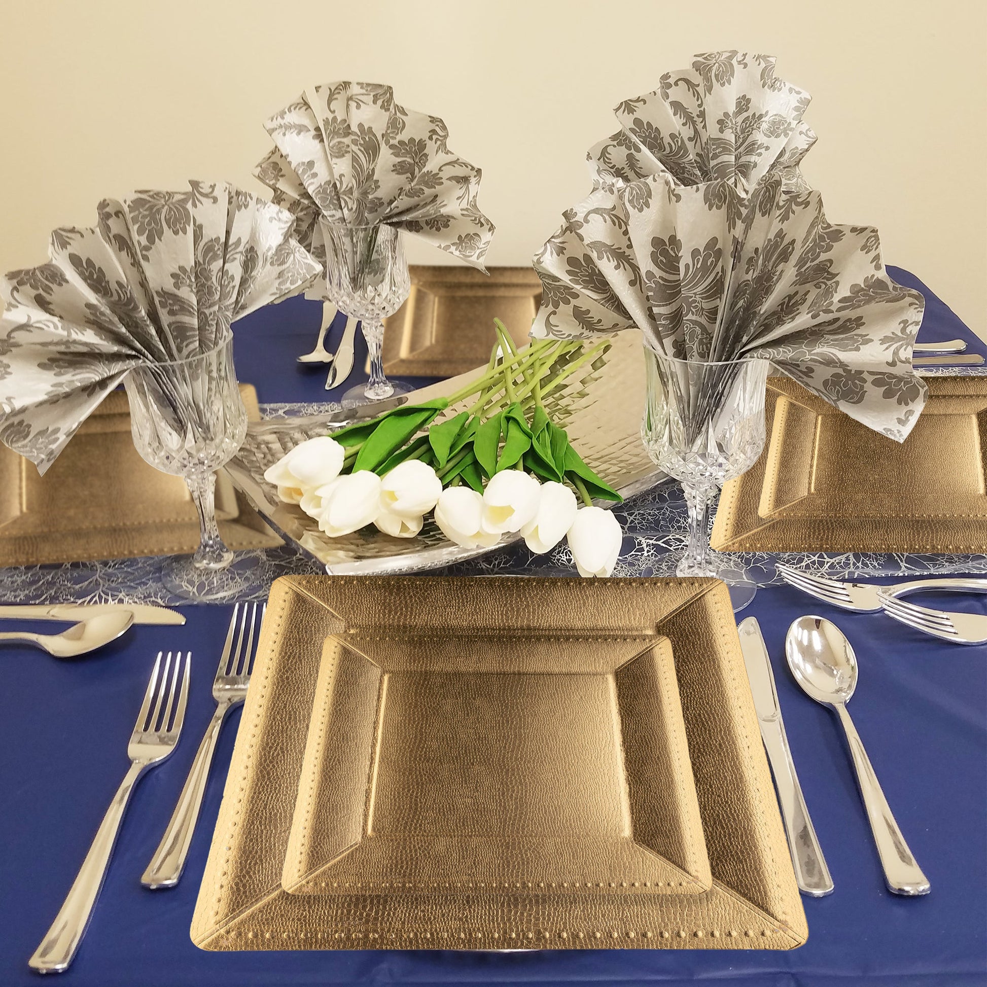 13" gold edge chargers displayed at a formal dinner with linen napkins, glassware, and greenery centerpieces.