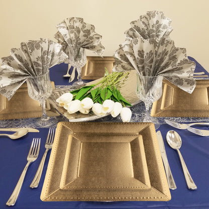 13" gold edge chargers displayed at a formal dinner with linen napkins, glassware, and greenery centerpieces.