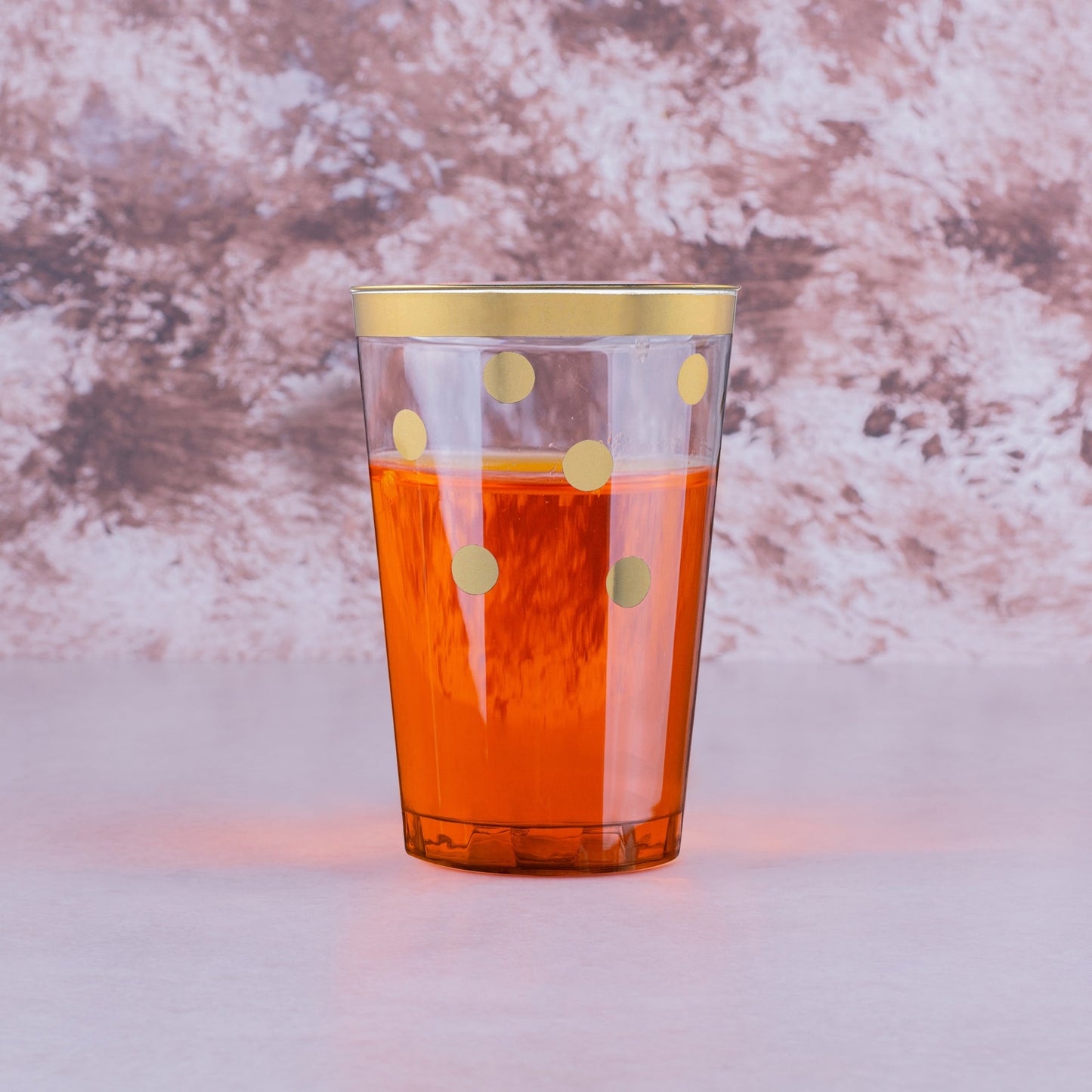 Stylish plastic tumblers with gold dots filled with drinks, enhancing a chic party scene